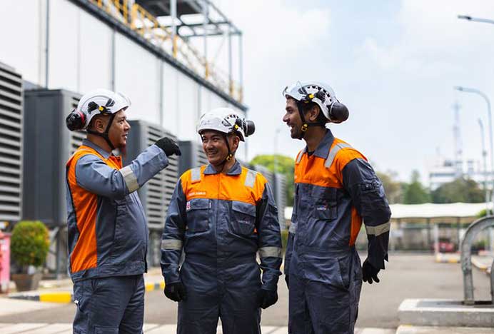 Three workers outside a power plant